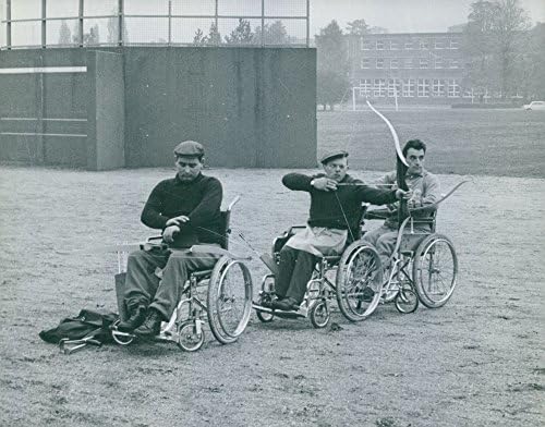 תצלום וינטג 'של גברים בכיסא הגלגלים שלהם, כל אחד אוחז בקשת וחץ .- 1964